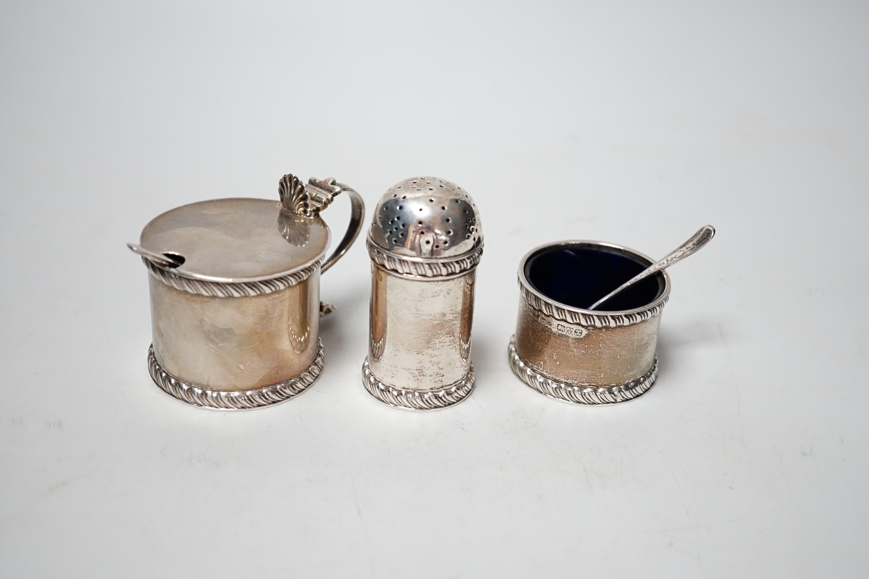 A George V three piece silver condiment set, Stokes & Ireland, Chester, 1923 and two associated spoons.